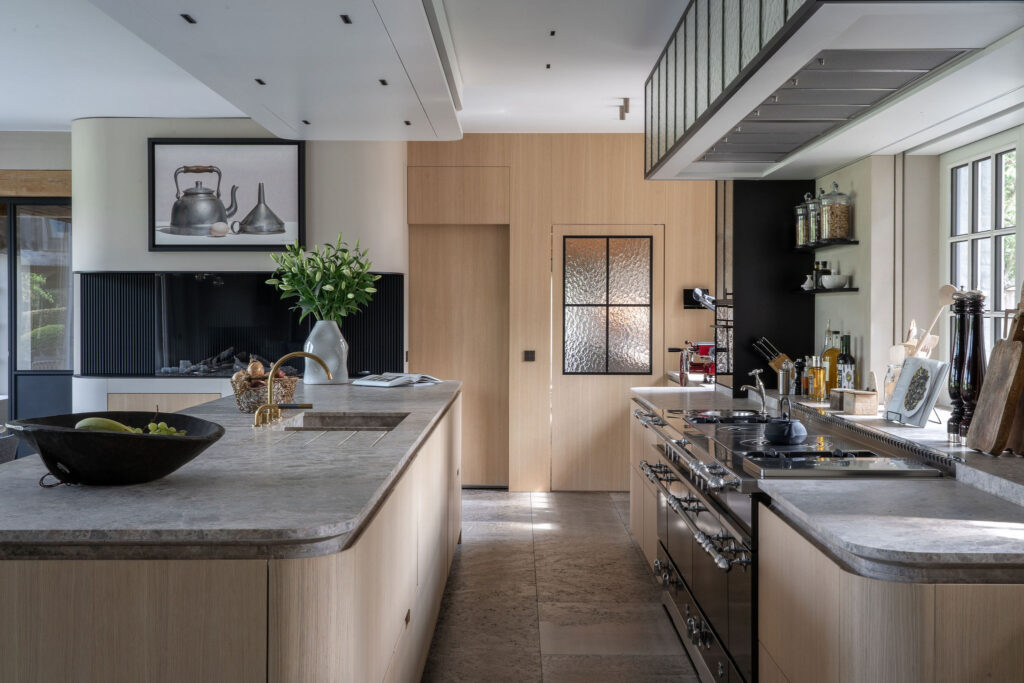 Moderne, ruime keuken met een natuurstenen werkblad en eikenhouten kasten, voorzien van hoogwaardige apparatuur.