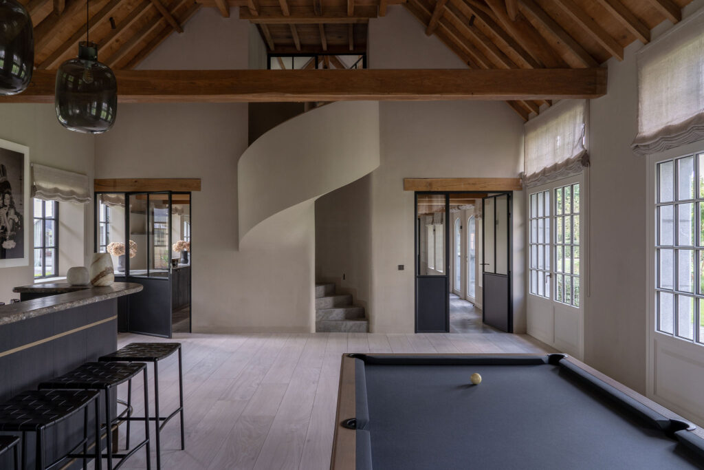 Veelzijdige ruimte waar ontspanning en gezelligheid centraal staan. Er is een oogverblindende bar, afgewerkt met hoogwaardige materialen. Een gezellige zithoek bij de open haard en een snookertafel voor spelplezier. Exclusief wonen op zijn best.